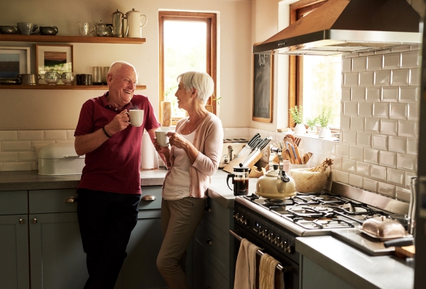 Senior adults smiling and conversing in their kitchen