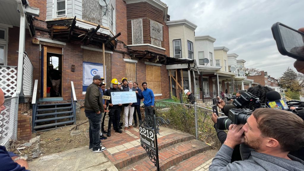 John Owens, ADT Senior Vice President, presents a $100,000 check to leaders of the Requity Foundation and vocational students participating in the Carver House rehabilitation project.