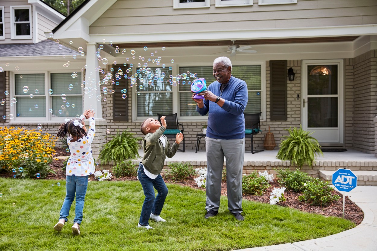 Older man Playing with Bubbles on Front Lawn with Children