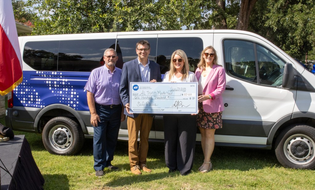 Irving Mayor Rick Stopfer (left) and All Things Made New Executive Director Michelle Flores (second from right) accept a $100,000 donation from ADT's Dave Scott and Amber Weaver. ADT also donated the passenger van in the background and ADT+ Security Systems.